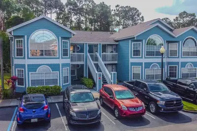 a blue house with cars parked in a parking lot at LOVE AT FIRST SIGHT! NEW Disney Home, Sleeps 6, Pool, Patio, NO Steps, LOW Rates! in Kissimmee