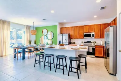 a kitchen with a large island with bar stools at 8BR Resort Home with Games Room and BBQ in Kissimmee