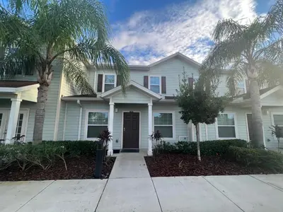 a white house with palm trees in front of it at Lovely and Cozy Townhome Near Disney Parks in Kissimmee