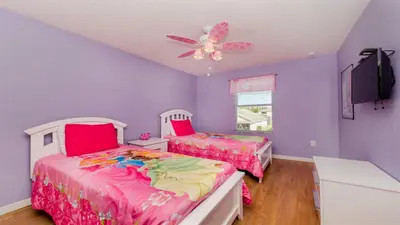 two beds in a purple room with a ceiling fan at Shvcc2 - Crystal Cove #2 - 7 Bed 45 Baths Villa in Kissimmee