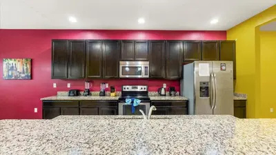 a kitchen with brown cabinets and a red wall at Shvcc1 - Crystal Cove #1 - 7 Bed 45 Baths Villa in Kissimmee