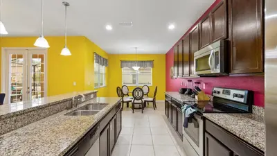 a kitchen with yellow and red walls and counters at Shvcc1 - Crystal Cove #1 - 7 Bed 45 Baths Villa in Kissimmee