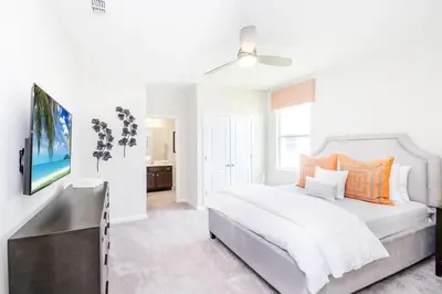 a white bedroom with a bed and a flat screen tv at 15BR Mansion Home with Pool & Hot Tub-near Disney in Kissimmee