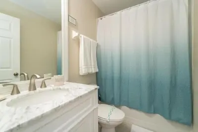 a bathroom with a blue shower curtain and a toilet at Callaghan Cantina home in Orlando