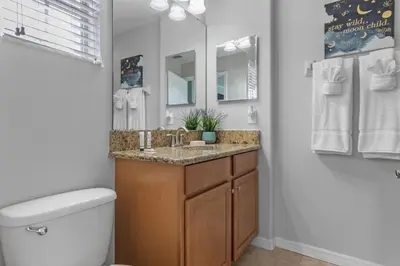 a bathroom with a sink and a toilet and a mirror at New listing 5 mi from Disney,Free Arcades, HeatedPool & Water park in Kissimmee