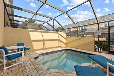 a swimming pool with a table and chairs next to a building at The Wish House, just miles from Disney World in Orlando