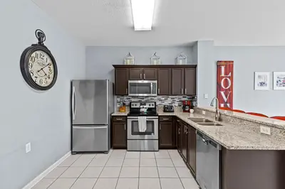 a kitchen with stainless steel appliances and a clock at The Wish House, just miles from Disney World in Orlando