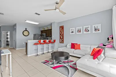 a living room with a white couch and red pillows at The Wish House, just miles from Disney World in Orlando