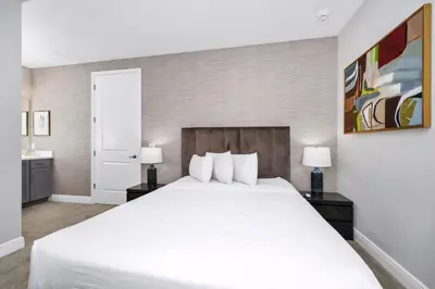 a bedroom with a large white bed and two lamps at Elite Home Near Disney With Theater Room, Game Room And Private Pool With Water Park Access At Encore Resorts Reunion - 200Au in Kissimmee