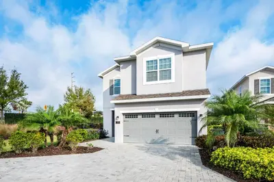a white house with a garage at Lovely Home Near Disney With Private Pool, Water Park & Resort Access At Encore Resort Reunion - 7423Mr in Kissimmee