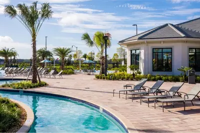 a resort pool with lounge chairs and palm trees at Amazing 6BR Villa @ Storey Lake Resort Near Disney in Kissimmee
