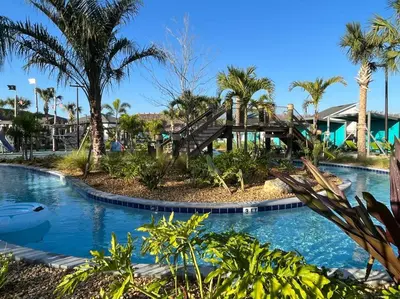 a resort pool with a wooden bridge and palm trees at Amazing 6BR Villa @ Storey Lake Resort Near Disney in Kissimmee