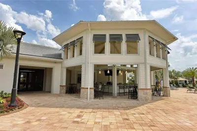 a white house with tables and chairs in front of it at Amazing 6BR Villa @ Storey Lake Resort Near Disney in Kissimmee