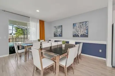 a dining room with a table and white chairs at Serene Sunsets Villa - E04 in Kissimmee