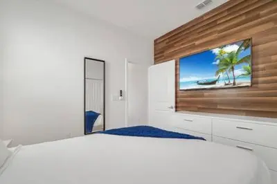 a white bedroom with a large bed with a picture of a beach at Serene Sunsets Villa - E04 in Kissimmee