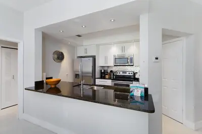 a kitchen with white cabinets and a black counter top at One in a Minion #102 in Orlando