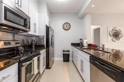 a kitchen with white cabinets and a clock on the wall at Mickey Mouse #104 in Orlando