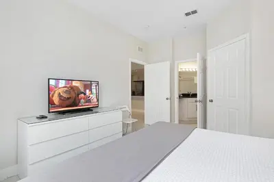 a white bedroom with a flat screen tv on a dresser at Windsor Hills Resort #202 in Orlando