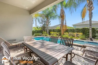 a patio with a table and chairs and a swimming pool at 7594 Oasis 8BD Villa- poolspa in Orlando