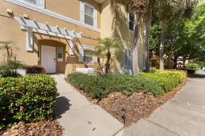 a building with trees and bushes next to a sidewalk at *PRIVATE POOL* Disney10min - Magical Mickey themed home in Kissimmee