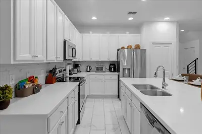 a white kitchen with white cabinets and a sink at 5BR Family Home with Pool & Hot Tub Near Disney in Kissimmee