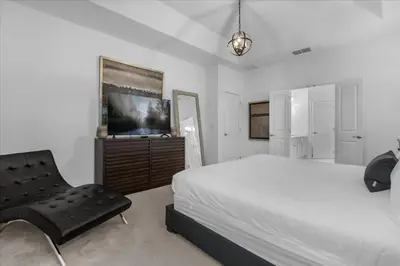 a bedroom with a bed and a chair and a television at 5BR Family Home with Pool & Hot Tub Near Disney in Kissimmee