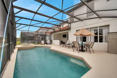 a swimming pool with a patio with a table and chairs at 6 Bedroom Luxury Pool Home, Ensuite Bathrooms in Kissimmee