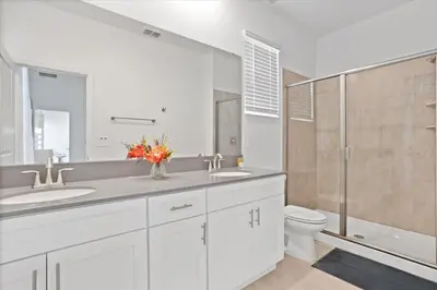 a bathroom with two sinks and a toilet and a shower at Modern Resort House Pool Wi-Fi Minutes to Disney in Kissimmee