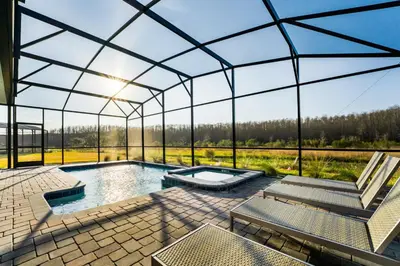 a glass house with a swimming pool and a patio at Amazing 8br w pool theater game room by Disney in Kissimmee