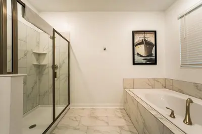 a white bathroom with a tub and a shower at Amazing 8br w pool theater game room by Disney in Kissimmee
