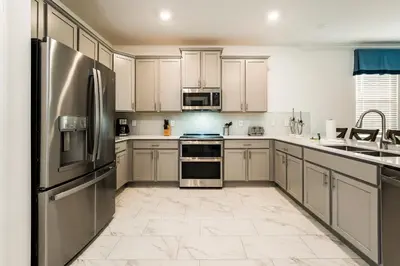 a kitchen with stainless steel appliances and white cabinets at Amazing 8br w pool theater game room by Disney in Kissimmee