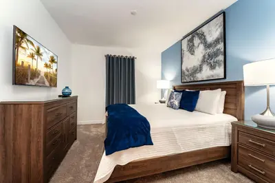a bedroom with a large bed and a dresser at Amazing 8br villa w theme rms game room theater in Kissimmee