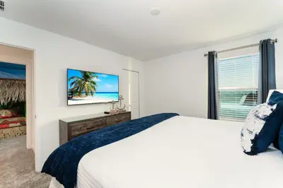 a bedroom with a bed and a flat screen tv at Amazing 8br villa w theme rms game room theater in Kissimmee