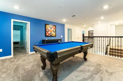 a pool table in a room with a blue wall at Amazing 8br villa w theme rms game room theater in Kissimmee