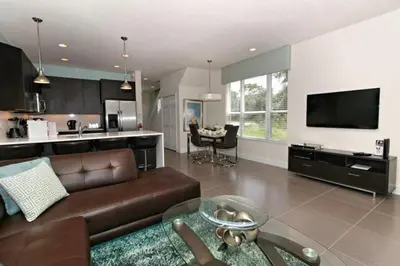 a living room with a brown couch and a kitchen at Serenity 3 Bed 3 Bath Townhome With Pool, Private Balcony, Clubhouse, Communal Pool, Conservation View, Disney 15 Mins By Orlando Holiday Rental, in Orlando
