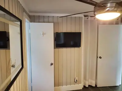 a room with a television on a wall with a door at Beautiful cottage near Lake Louisa & mins from Disney, Vehicle Rental Available in Clermont