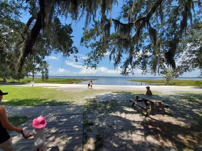 a woman standing next to a picnic table on a beach at Beautiful cottage near Lake Louisa & mins from Disney, Vehicle Rental Available in Clermont