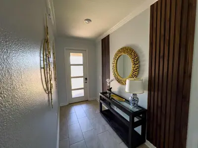 a hallway with a mirror and a table with a lamp at 5BR Villa with Game Room and Spa, 12 Min to Disney in Kissimmee