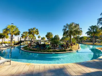 a large swimming pool with palm trees in a resort at 5BR Villa with Game Room and Spa, 12 Min to Disney in Kissimmee