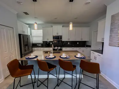 a kitchen with a table and chairs in it at 5BR Villa with Game Room and Spa, 12 Min to Disney in Kissimmee