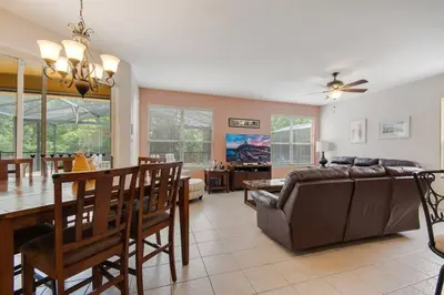 a living room and dining room with a couch and a table at Large Pool Deck * All Rooms w/ Private Bathroom in Kissimmee