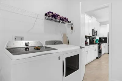 a kitchen with white cabinets and a stove top oven at Stylish Resort Villa w Pool Near Disney Gated 5BR in Kissimmee