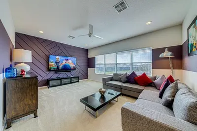 a living room with a couch and a flat screen tv at #371-Stunning 6 bed with modern decor, south facing pool and spa overlooking water in Kissimmee