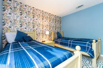 a bedroom with two beds and a wall covered in wallpaper at 2739SKP New Emerald Island 4 Bedroom townhouse in Kissimmee