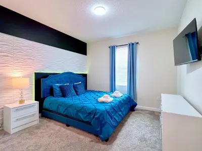 a bedroom with a blue bed and a tv at Eight-Bedroom House in Kissimmee