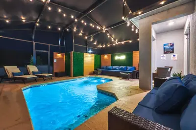 a large swimming pool in a room with a couch and furniture at Brand New Corner Lot Pond View Vacation Home in Kissimmee