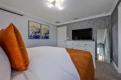 a bedroom with a white bed and a flat screen tv at Brand New Corner Lot Pond View Vacation Home in Kissimmee