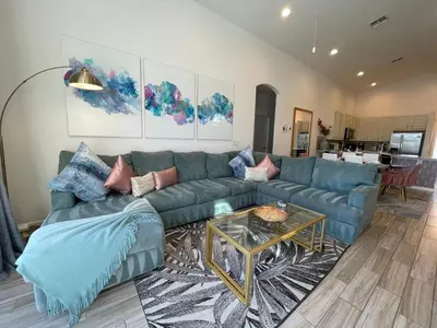 a living room with a blue couch and a table at #372-Welcome to Lightwater Villa, your Modern Disney Vacation home! South-Facing Pool & Spa Overlooking Lake in Kissimmee