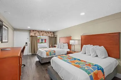 a hotel room with two beds and a desk at Travelodge by Wyndham Kissimmee Orlando in Kissimmee