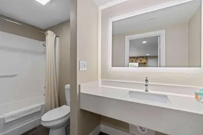 a bathroom with a sink and a toilet and a mirror at Travelodge by Wyndham Kissimmee Orlando in Kissimmee